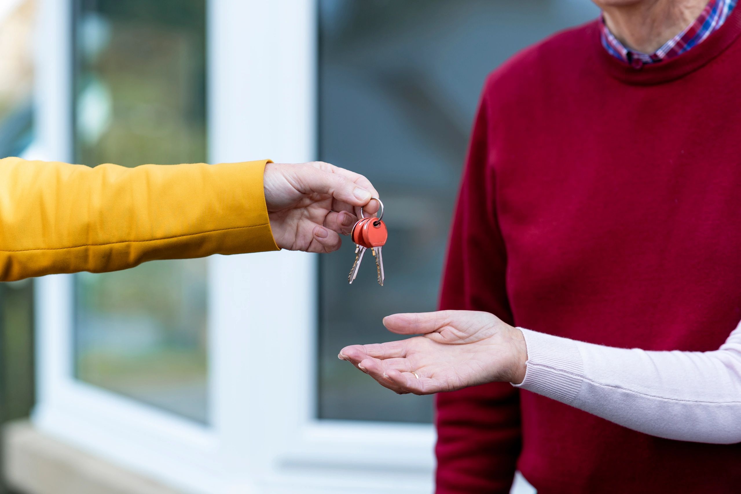 Hands receiving house keys symbolizing housing stability